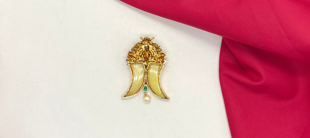 Gold Puligoru tiger nail, accented with rubies, emeralds, and a pearl drop Locket