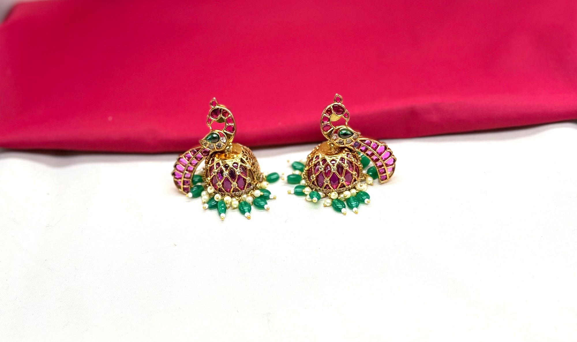 Matte finishing peacock-inspired pink Gemstones and pearl drops Jhumka’s